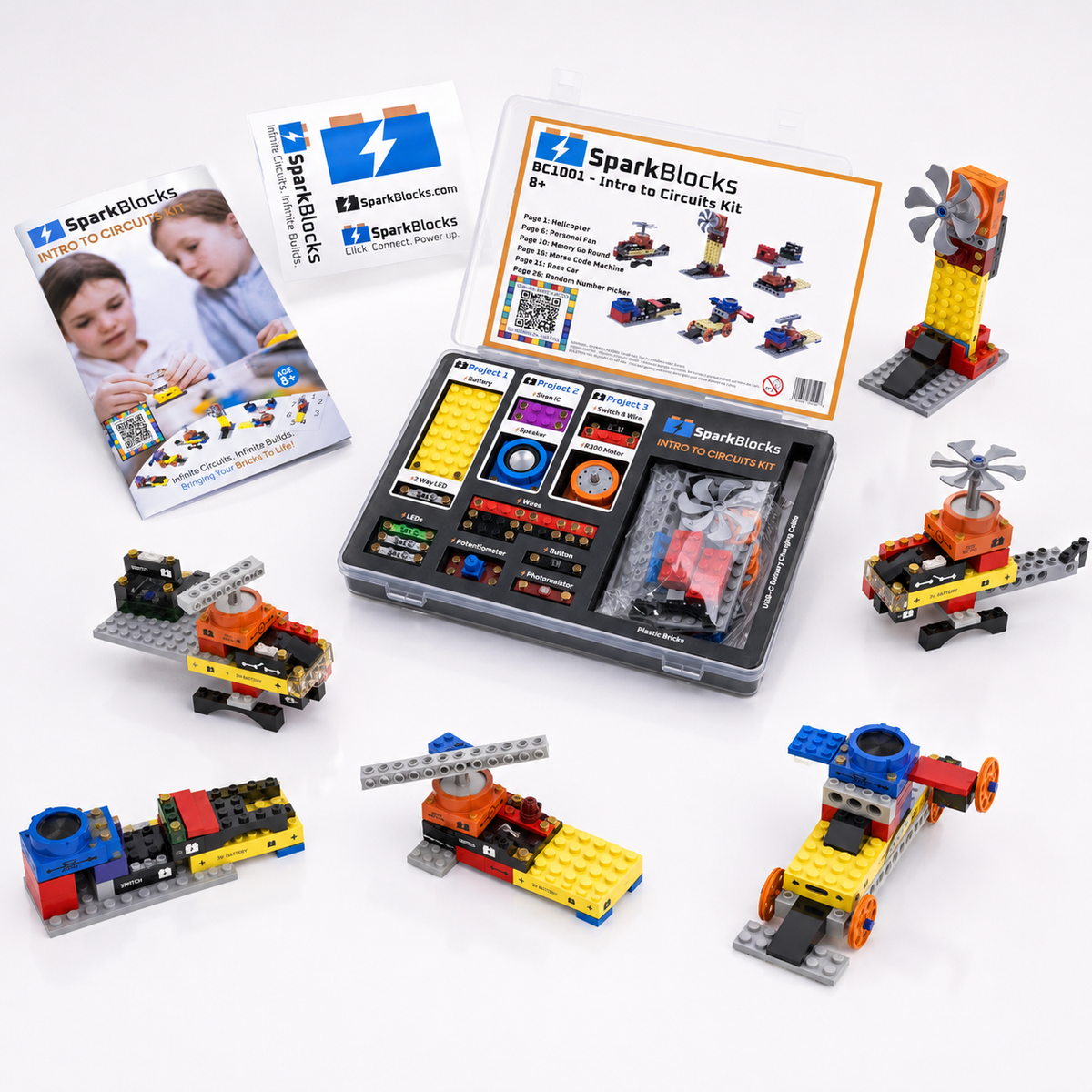 SparkBlocks intro to circuits kit shown with its open control panel, instruction booklet, and several small build vehicles built from colorful blocks on a white background.