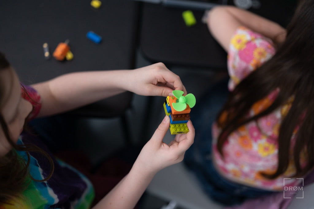 Two children playing with colorful building blocks on a dark surface.