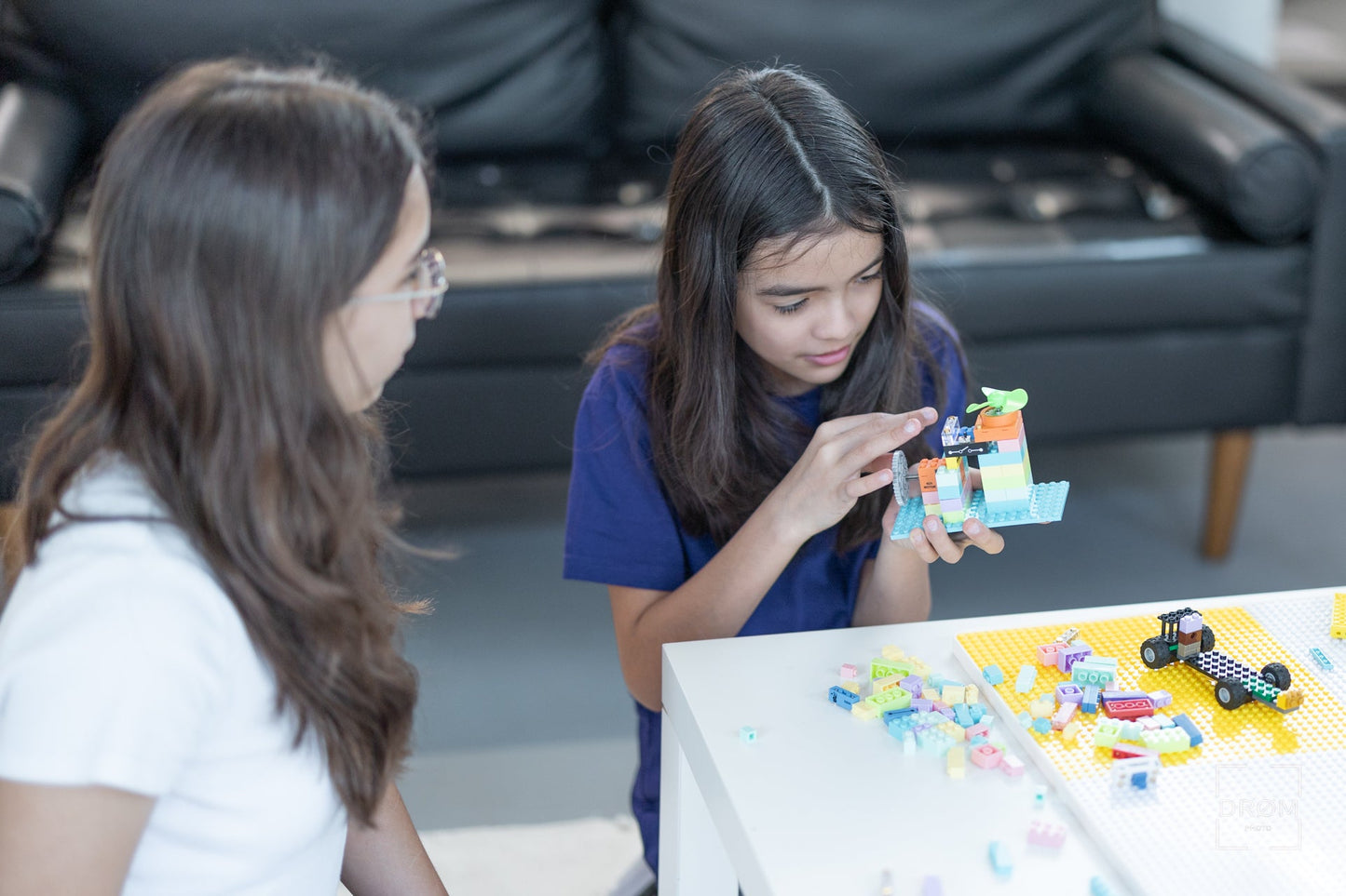 Two girls playing with SparkBlock on a table in a living room.