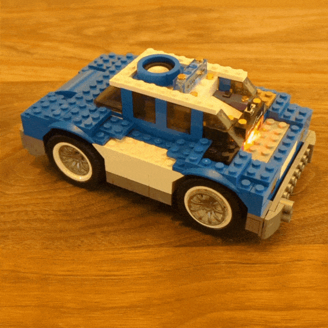 Child pushing a button to light a light and then sliding a switch to turn on a motor to allow the patrol car to drive off