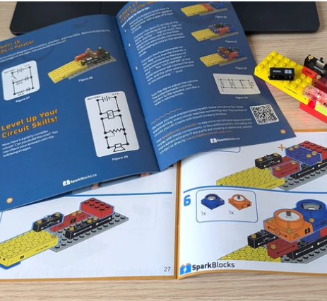 The printed SparkBlocks Learning Guide open beside the visual build instruction booklet