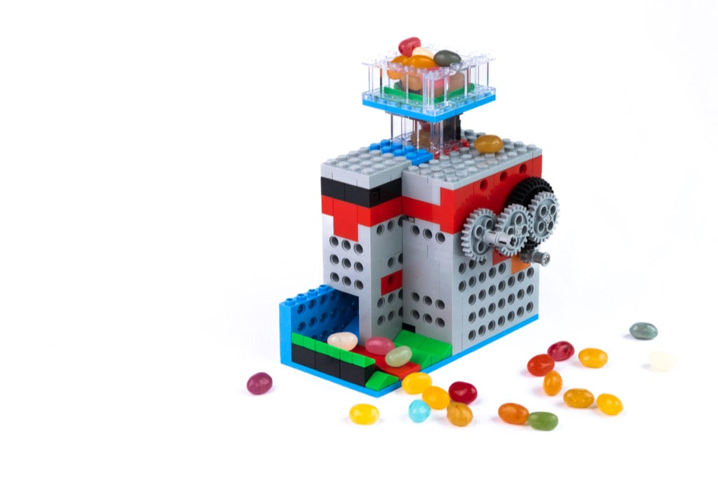 Toy building set with colorful blocks and jelly beans on a white background