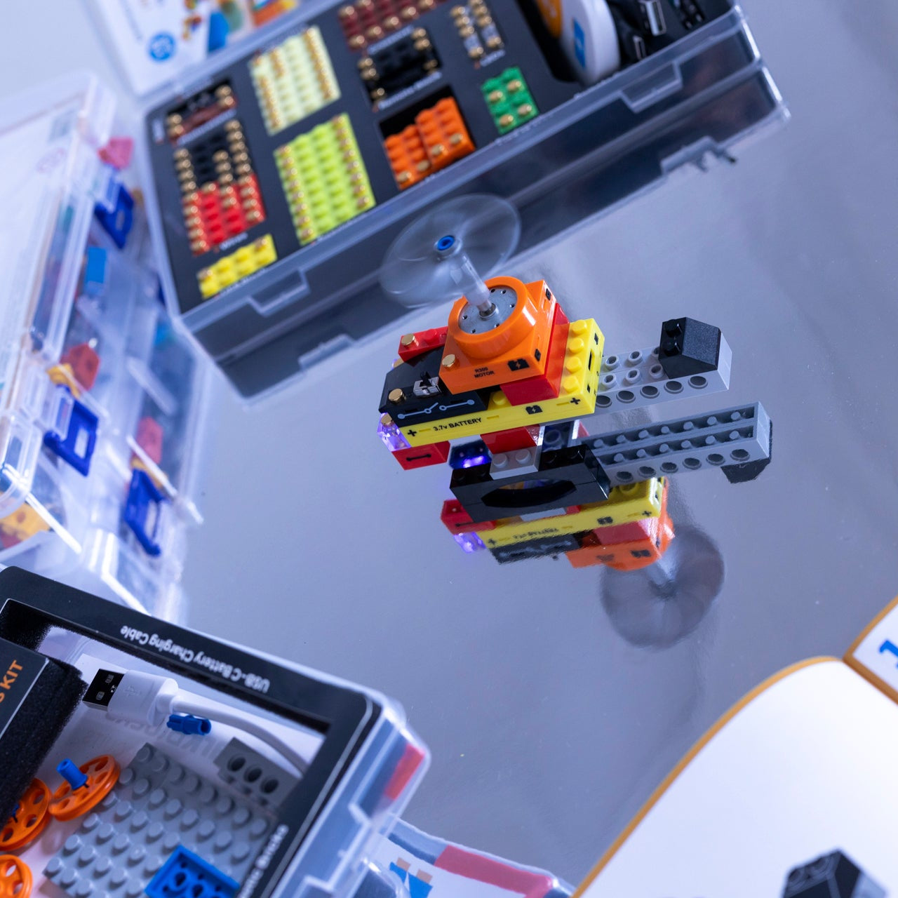 Close-up of a helicopter model assembled with building blocks and manuals on a reflective surface.