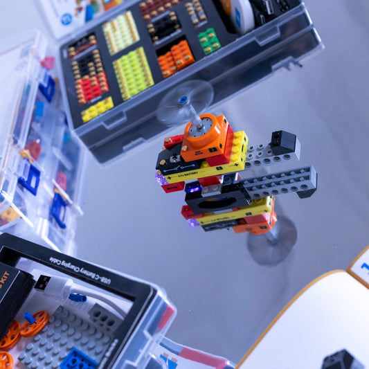 Close-up of a helicopter model assembled with building blocks and manuals on a reflective surface.