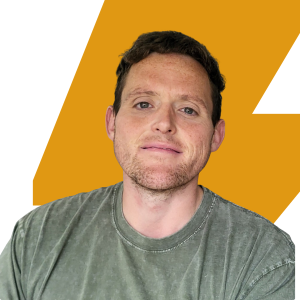 A man with short brown hair and light stubble, wearing a faded olive green t-shirt, shown in a close-up portrait against a graphic background of yellow and white.