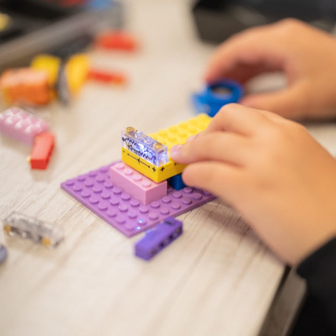 A student using a smart classroom kit to assemble electronic building blocks, demonstrating a hands-on classroom circuit kit activity for screen-free learning.