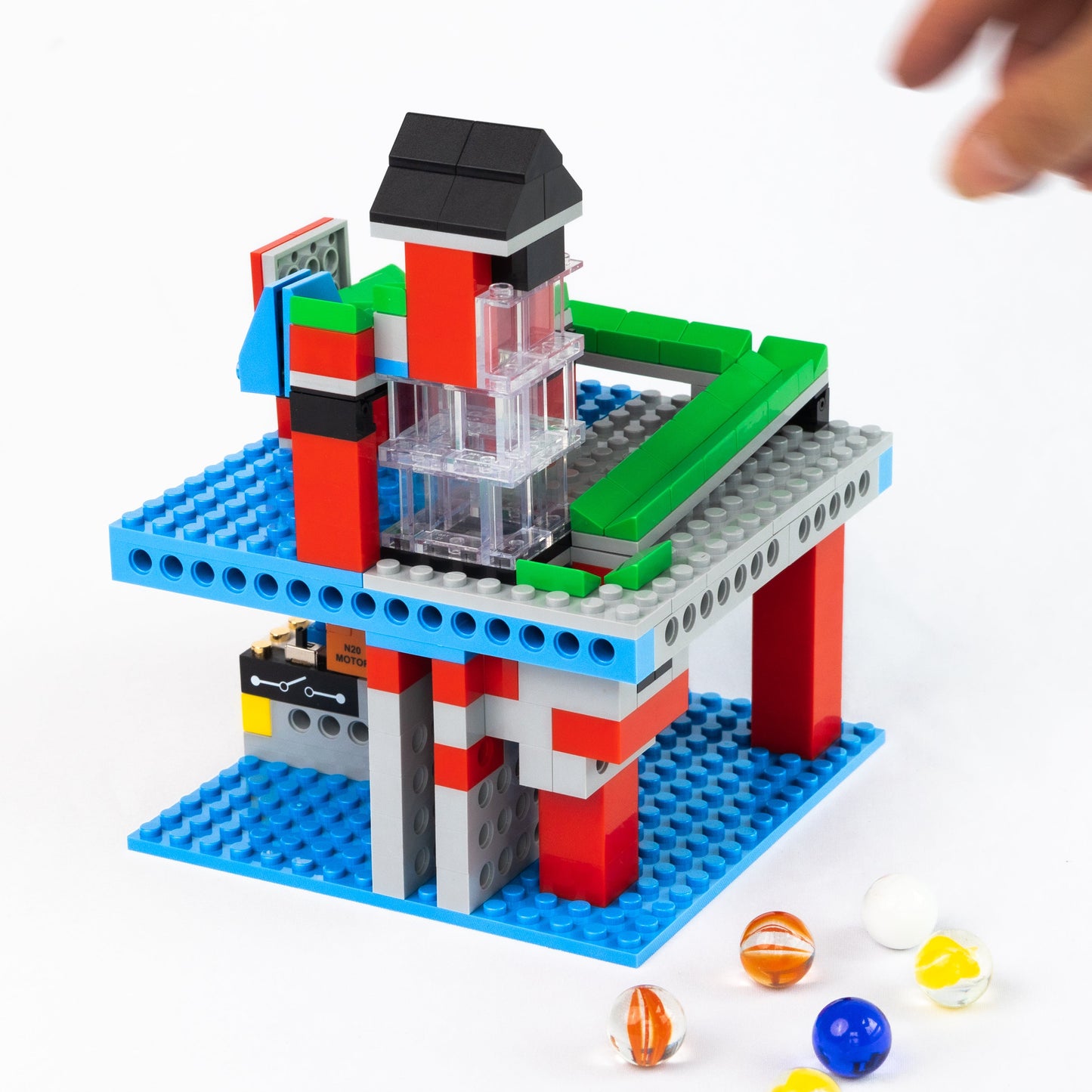 A hand interacting with a functional infinite loop marble run from the 3-in-1 Mighty Machines Kit, a motorized STEM toy that provides a screen-free and hands-on learning experience with the ultimate theme bundle.