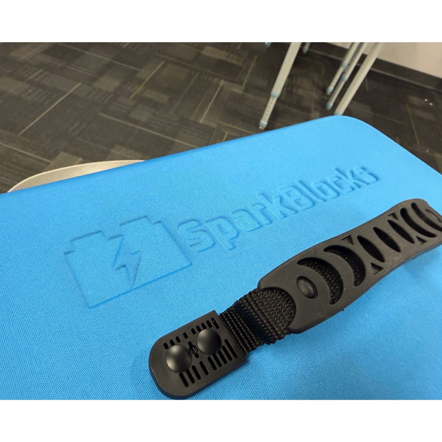 A textured black organization strap from a smart classroom kit, positioned on a blue surface with white 'SparkBlocks' branding.