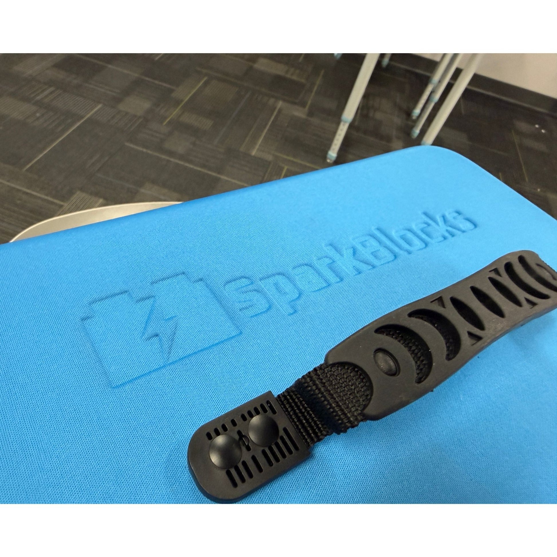 A textured black organization strap from a smart classroom kit, positioned on a blue surface with white 'SparkBlocks' branding.